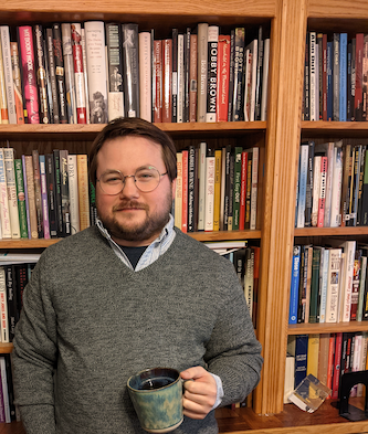 Administrator of Our Phoenix Foundation, standing proudly in front of a bookshelf filled with impactful sexual abuse narratives.